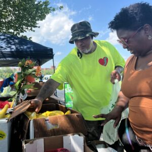 Man and woman picking fruits at a fruit stand