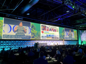 Woman presenting on stage at a large conference