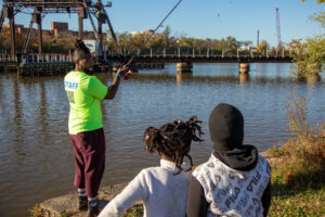 Man fishing in a river with two youths watching